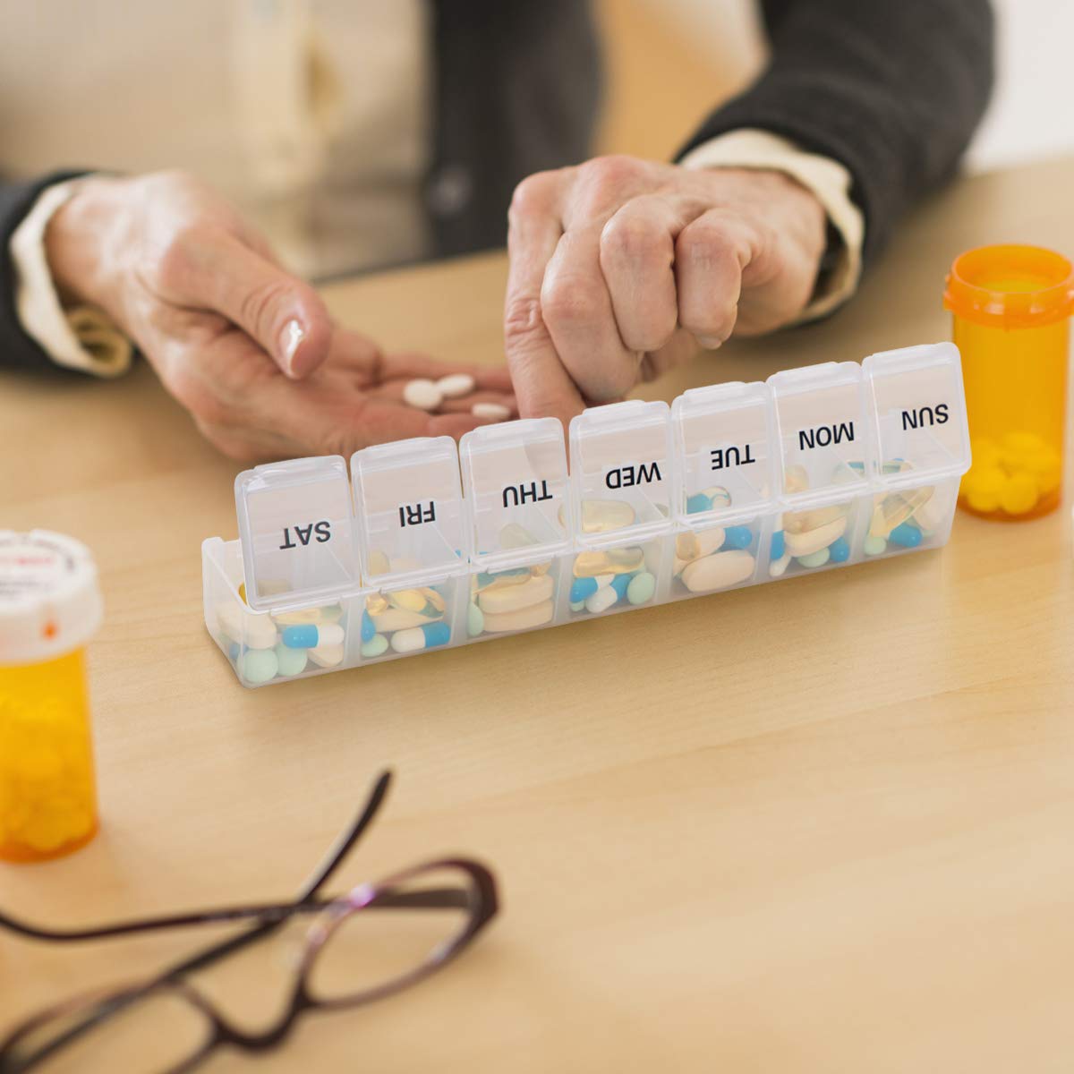 a hand holding a pill container with text: 'SUN MON TUE WED THU FRI SAT'