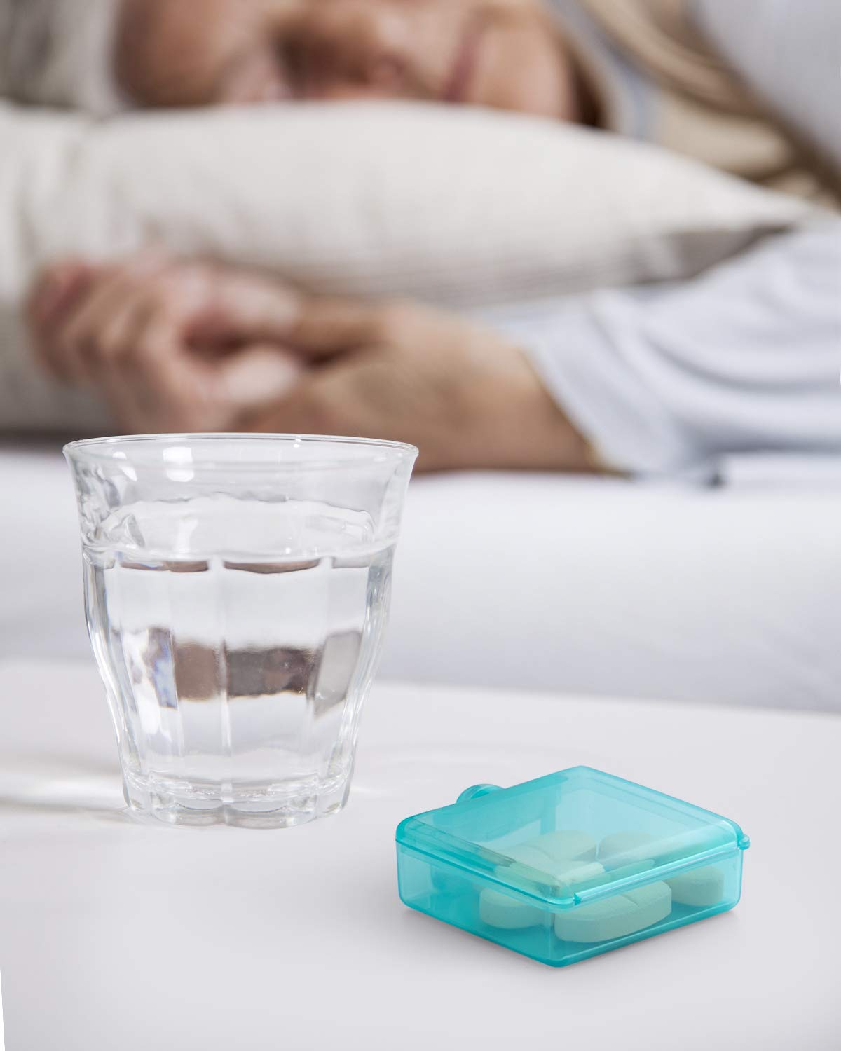 a glass of water and pills on a table