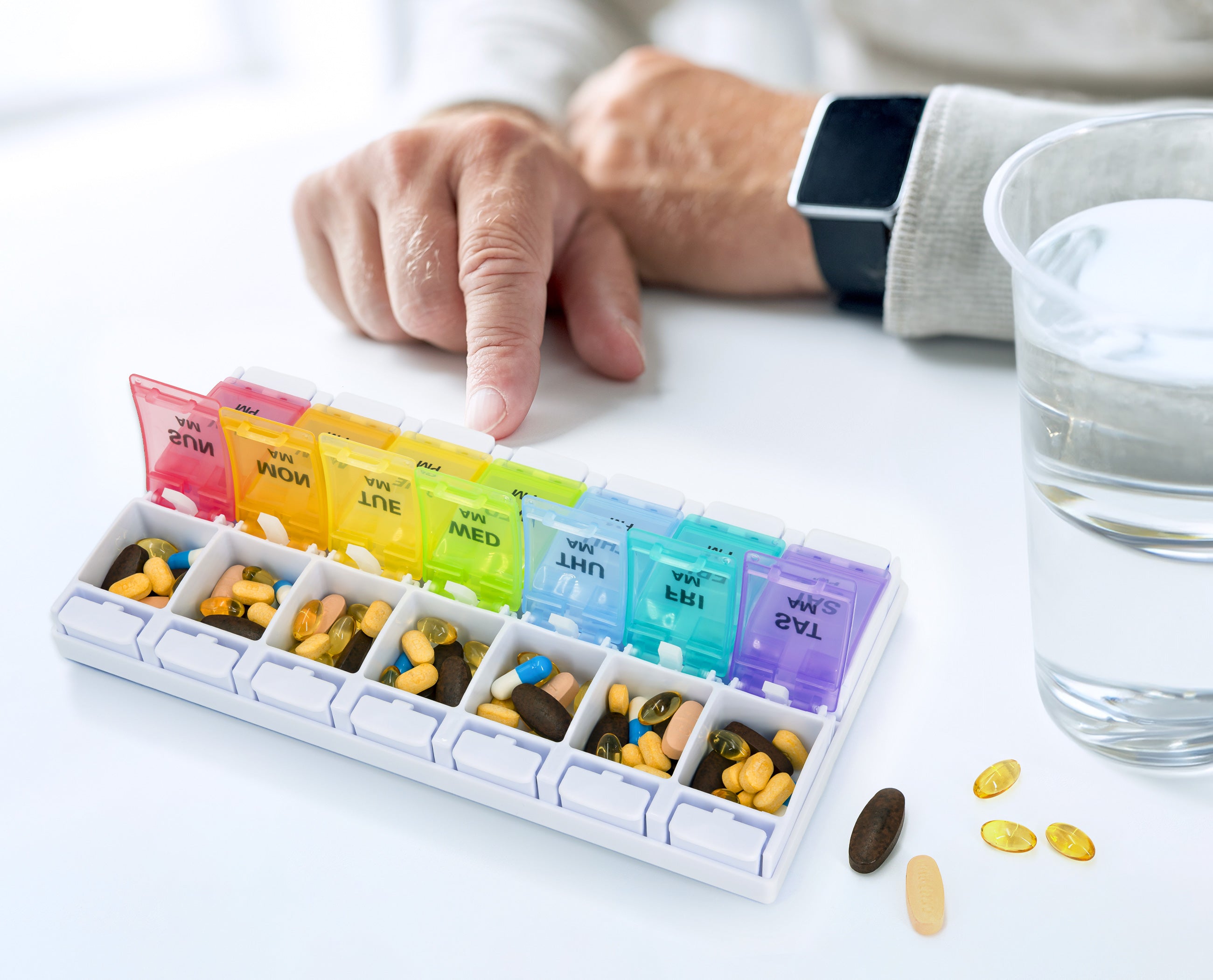 older man using push open rainbow pill case